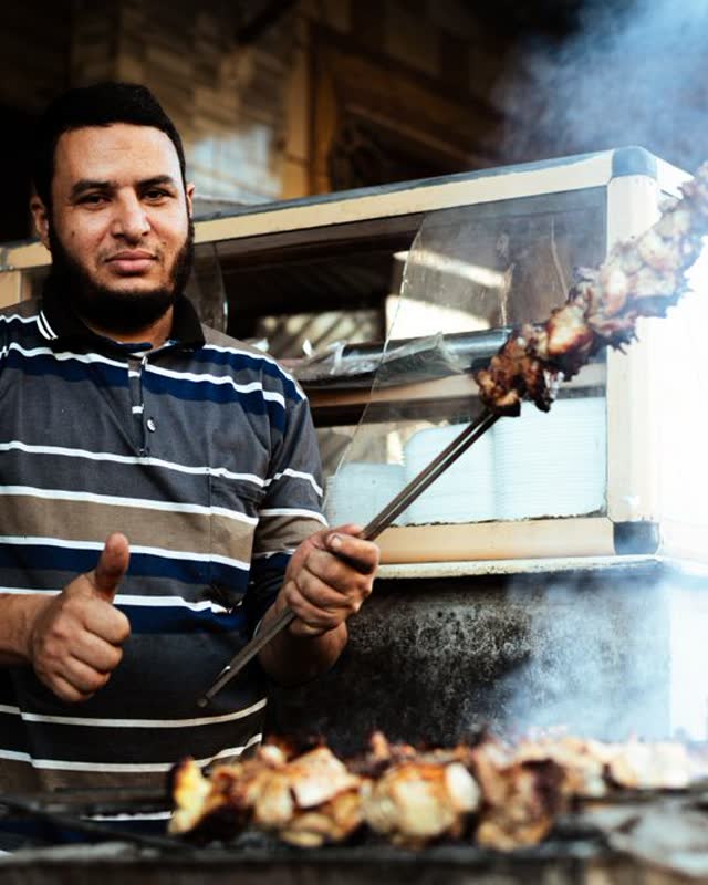 A street food cook grilling skewers in Cairo