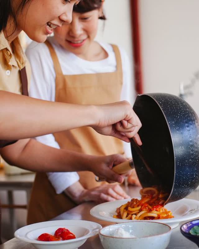 Two people plating pasta in a cooking class