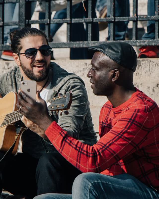Two friends playing guitar on the street